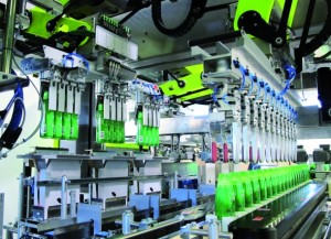 The Transmodul with the erected cartons moves on to the loading station. A TLM F2 robot picks up four bottles at a time from the grouping table and places them in the cartons.